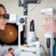 Optometrist giving eye exam to senior patient.