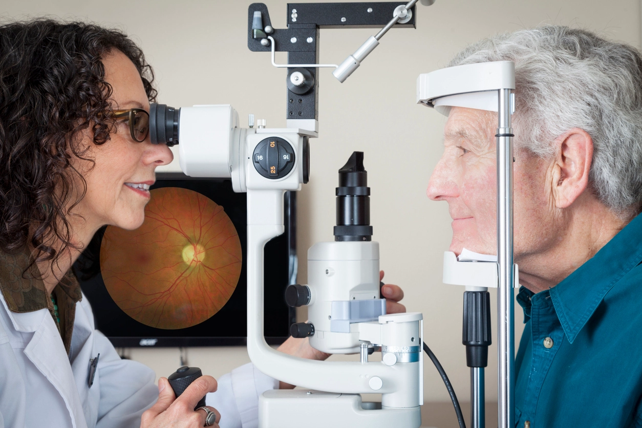 Optometrist giving eye exam to senior patient.