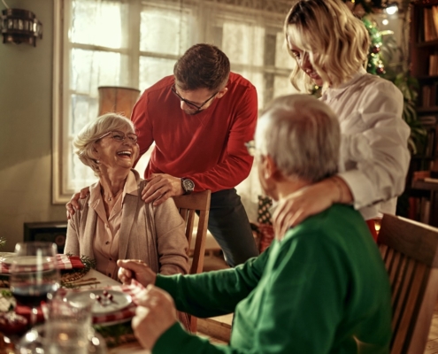 Senior couple and young adult couple hugging over Christmas dinner.