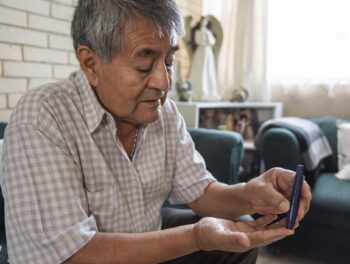 close up, older adult draws blood from a finger to check his blood sugar levels. health care concept from home