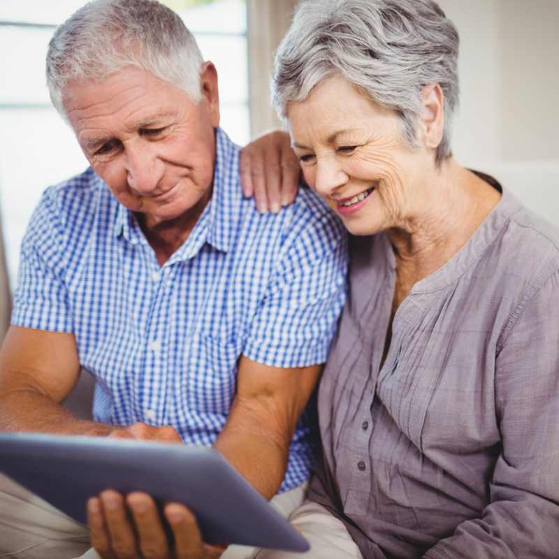 Senior couple on couch looking at health team medicare advantage plans on their mobile device