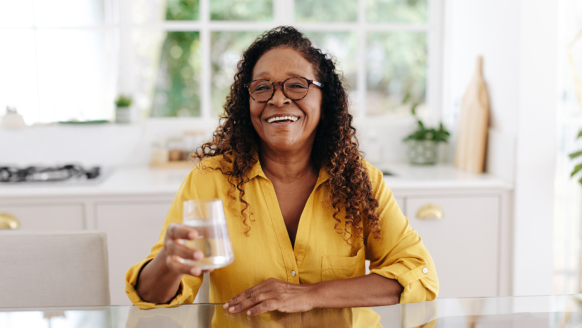 Senior woman drinking water at home.