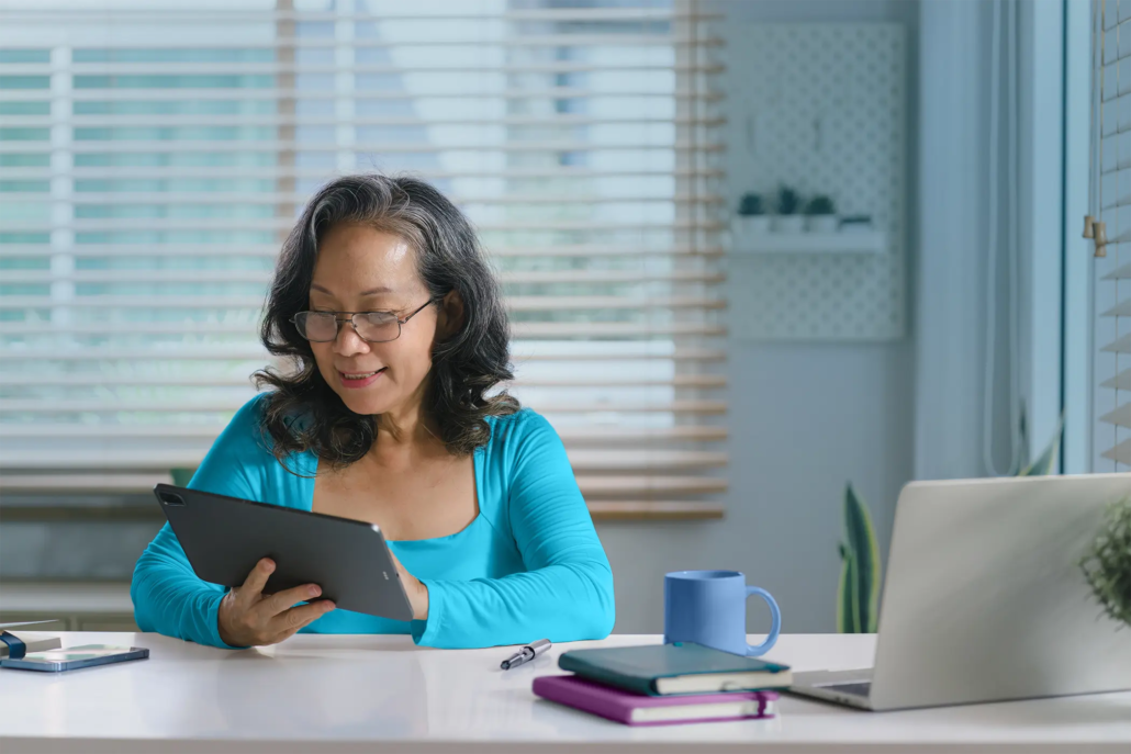 Senior woman works on her memory fitness on tablet at a desk.