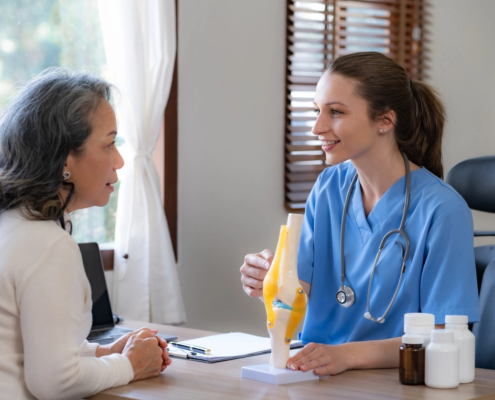 Female doctor is introducing an elderly Asian female patient about bone diseases and treatment method and medicine details.