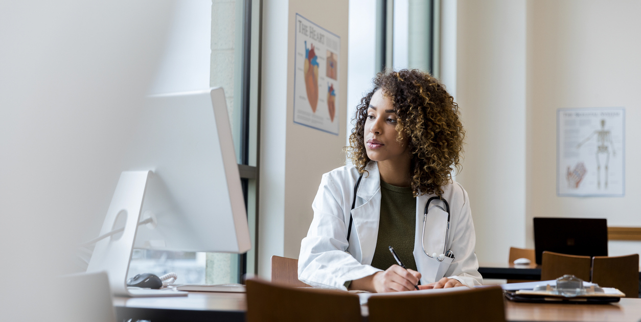 Focused Female Doctor Working at Computer in Medical Office